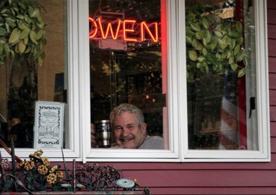 Owen, the founder of Box Lunch looking out the restaurant window with his name written in lights above his head